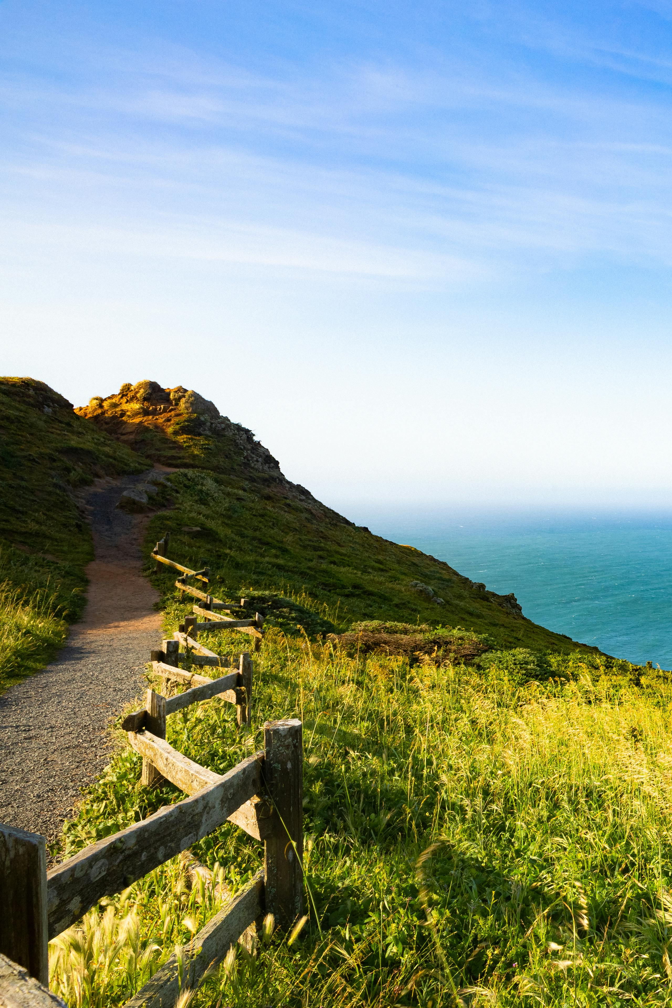 Coastal trail with ocean view, hiker with daypack