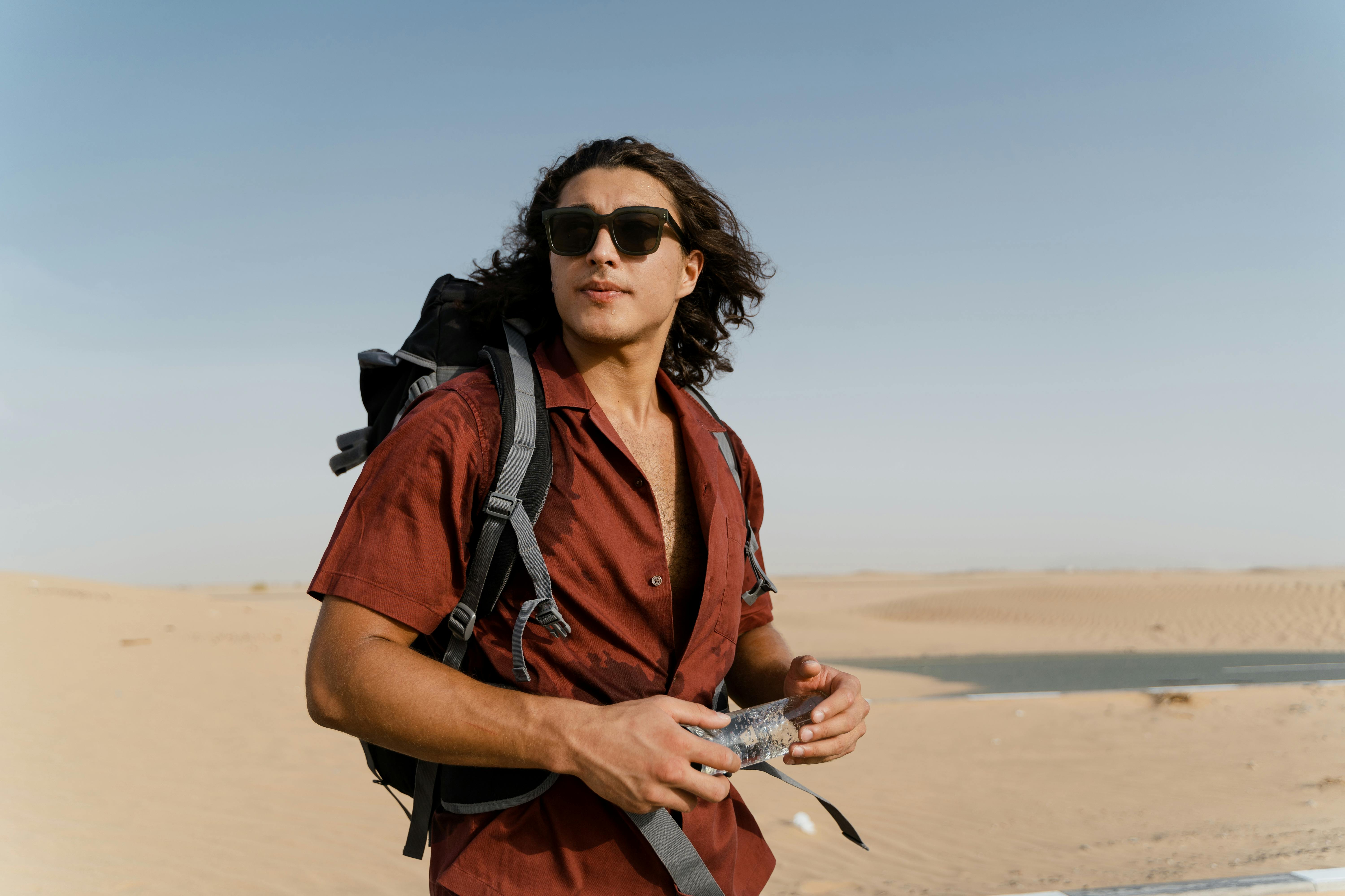 Hiker in desert landscape with sunglasses and hat in bright sun